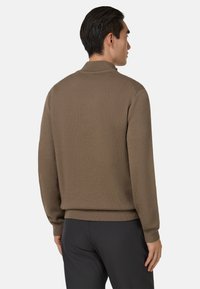 Brązowy sweter o fakturowanej strukturze, z kołnierzem stójkowym, ściągaczami przy mankietach i u dołu. Projekt charakteryzuje się wzorem w romby, wykonanym z miękkiego dzianiny.