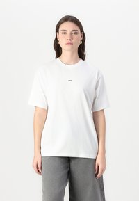 White cotton t-shirt with short sleeves and a crew neck, featuring a small black "JJXX" logo on the chest. Simple design and relaxed fit.