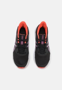 Baskets de sport noires avec une tige en mesh, des accents roses et une semelle blanche. Elles possèdent un col rembourré et une doublure intérieure contrastante en orange.