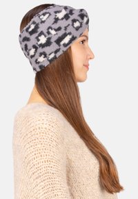 Bandeau en polaire noir et gris à motif, conçu pour recouvrir les oreilles, avec une texture douce et une forme large pour le confort.