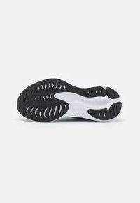 Black and white athletic shoe sole with textured grooves, featuring a rubber outer layer and flexible midsole design for traction.