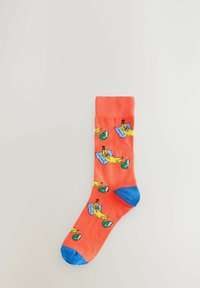 Koralle Baumwollsocken mit Cartoon-Bananen in blauen Liegestühlen, mit blauen Bündchen und Zehenakzenten. Weiche Textur, mittlere Wadenlänge.