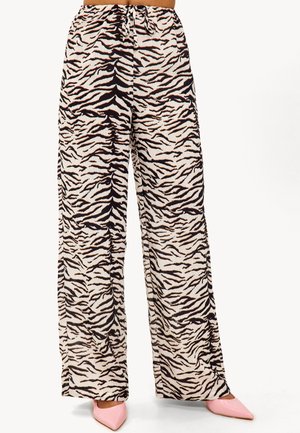 Un pantalon large en tissu crème avec un motif de rayures de tigre noir et orange, doté d'une taille élastique et d'un cordon de serrage.