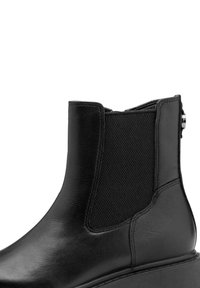 Bottine en cuir noir avec panneau latéral élastique et languette de tirage, présentant un bout arrondi lisse et un talon bas.