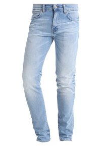 Ljust blå denimjeans med slim fit, femfickorsdesign, standard knapplås och dragkedja, samt subtil blekning vid låren.