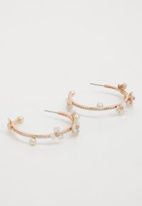 Rose gold hoop earrings featuring floral accents, pearl details, and a crystal-encrusted band. Lightweight metal with glossy texture.