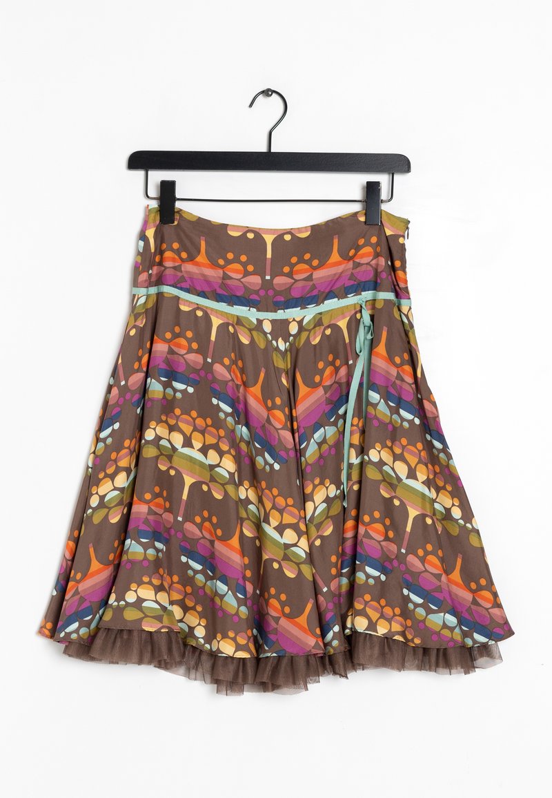 Jupe marron avec des motifs abstraits d’arbres colorés, une fermeture éclair latérale, un lien bleu aqua et un ourlet transparent à volants, suspendue sur un cintre noir.