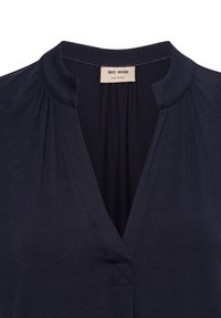 Camicia blu navy con scollo a V, texture morbida e dettagli plissettati sulle spalle. L'etichetta riporta "MOS MOSH".