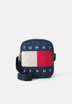 Mała kwadratowa granatowa torba na ramię z denimu z białym i czerwonym prostokątnym logo oraz napisem „Tommy Jeans”, zamkiem błyskawicznym i regulowanym paskiem.