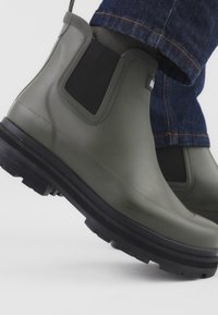 Vihreät kumipohjaiset nilkkasaappaat, joissa mustat joustavat paneelit ja kuvioidut pohjat, sileä viimeistely ja matala profiili.