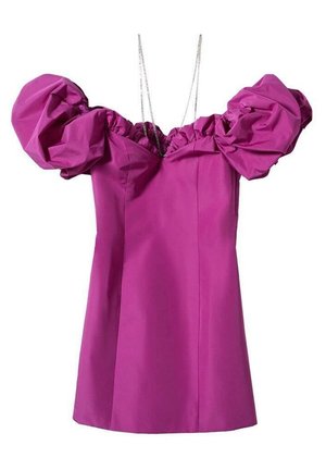 Vrouw die een korte, felpaarse off-shoulder jurk met pofmouwen draagt, zwarte doorschijnende panty's en zwarte open-teen hakken, staand op een vlakke vloer.