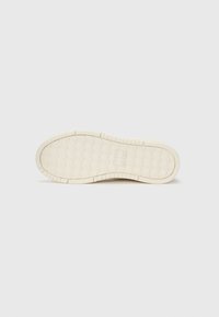White rubber shoe sole with a textured honeycomb pattern and grooves for grip. Features a flat profile and rounded toe design.
