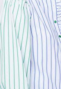 Stribet skjorte med en blanding af grønne og blå linjer på en hvid baggrund; blødt stof med knapdetalje og flæsekrave.