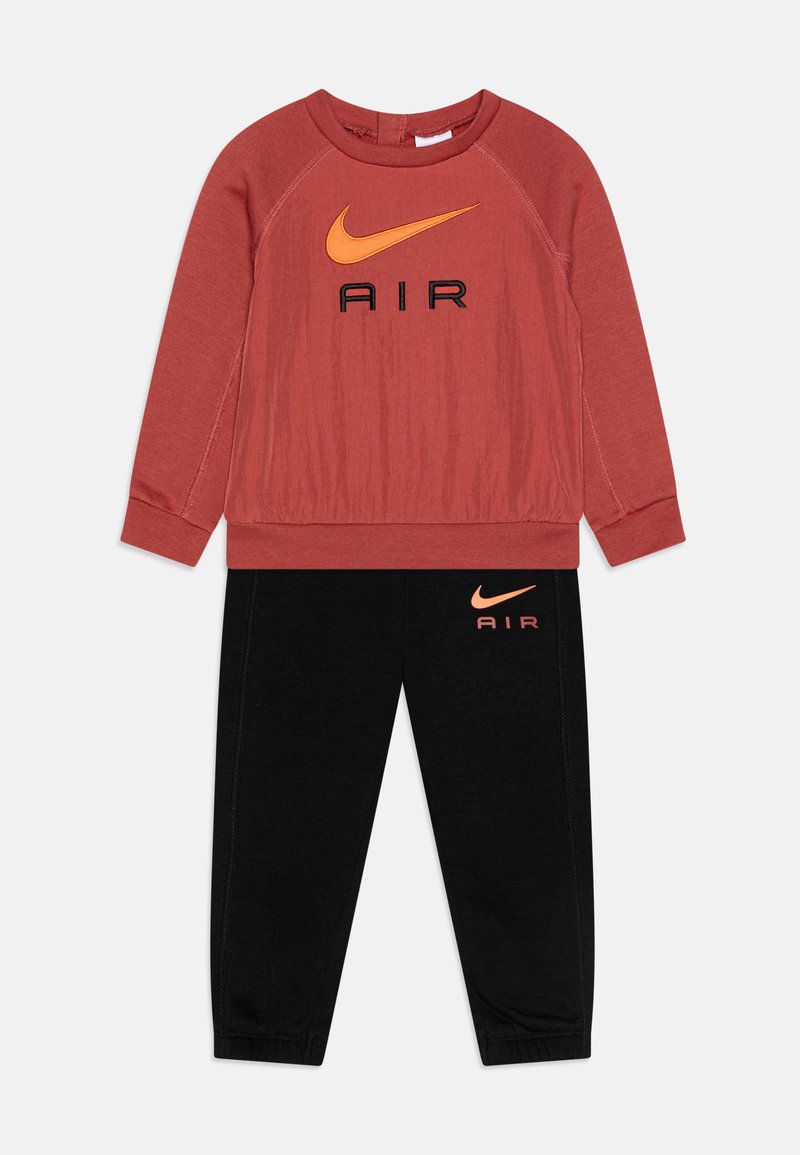 Red sweatshirt with orange Nike logo and black pants featuring matching logo, both made from soft fabric, casual fit, with ribbed cuffs.