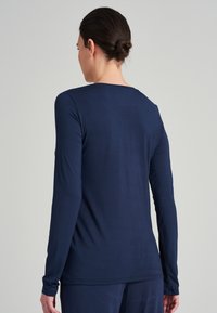 Marinblå långärmad topp med rund halsringning och mjukt tyg. Åtsittande design med långa ärmar och minimala detaljer.