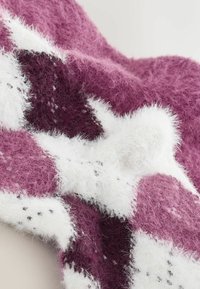 Tjekket tæppe i nuancer af dyb bordeaux og hvid, med en blød, fuzzy tekstur og et løst strikket mønster med synlige fibre.