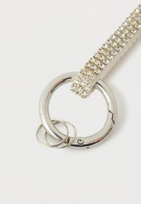 Rhinestone-encrusted metallic keyring with a circular design, featuring two smaller metal rings for attachment. Smooth, shiny surface.