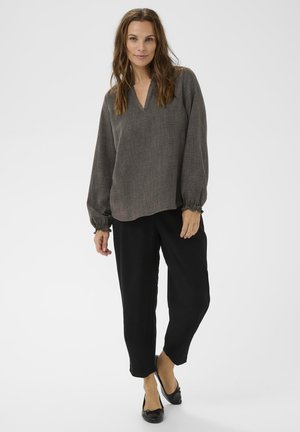 Grijze geweven blouse met een V-hals en pofmouwen, gecombineerd met zwarte relaxed-fit broek en zwarte platte schoenen. Gladde textuur, casual ontwerp.