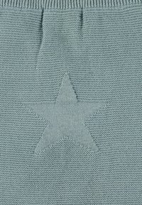 Helles blaues strickmaterial mit einem auffälligen sternumrissmuster. Die textur ist glatt mit einem gleichmäßigen stichdesign.