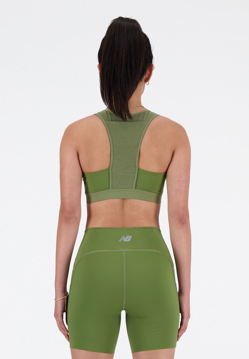 Olivgrüner Sport-BH mit Racerback-Design und elastischem Bund. Passende hochtaillierte Shorts mit einem Logo und glattem, dehnbarem Material.