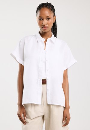 Witte linnen overhemd met korte mouwen, knoopsluiting, inkeping in de kraag en een ontspannen pasvorm. Gecombineerd met beige high-waisted broek.