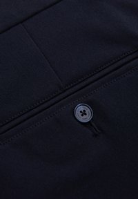 Navy stof close-up met een knop met bloemontwerp, een gestructureerd oppervlak en gestikte details.