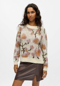 Blomstermønstrede strikkede trøje i off-white med pink og brune designs, med rund hals og ribbede manchetter; båret med en brun læderskørt.