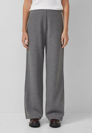 Graue weit geschnittene Hose aus weichem Stoff, mit lockerer Passform, hohem Bund und glatter Textur. Getragen mit dunklen Schuhen.