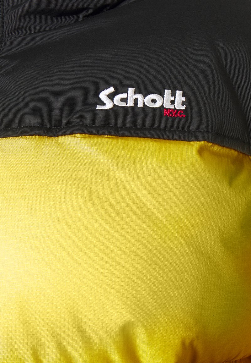 Tissu noir et jaune avec les logos brodés blancs "Schott" et un petit "N.Y.C." rouge sur la section noire.