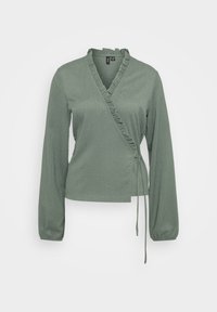 Blouse verte avec manches longues, un décolleté à volants et une taille ajustable avec lien. Fabriquée en tissu texturé avec une coupe ajustée.