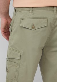 Lichtgroene cargobroek met zijzakken, een achterzak met flap en knoopsluiting. Gemaakt van gestructureerde stof en heeft een ontspannen pasvorm.