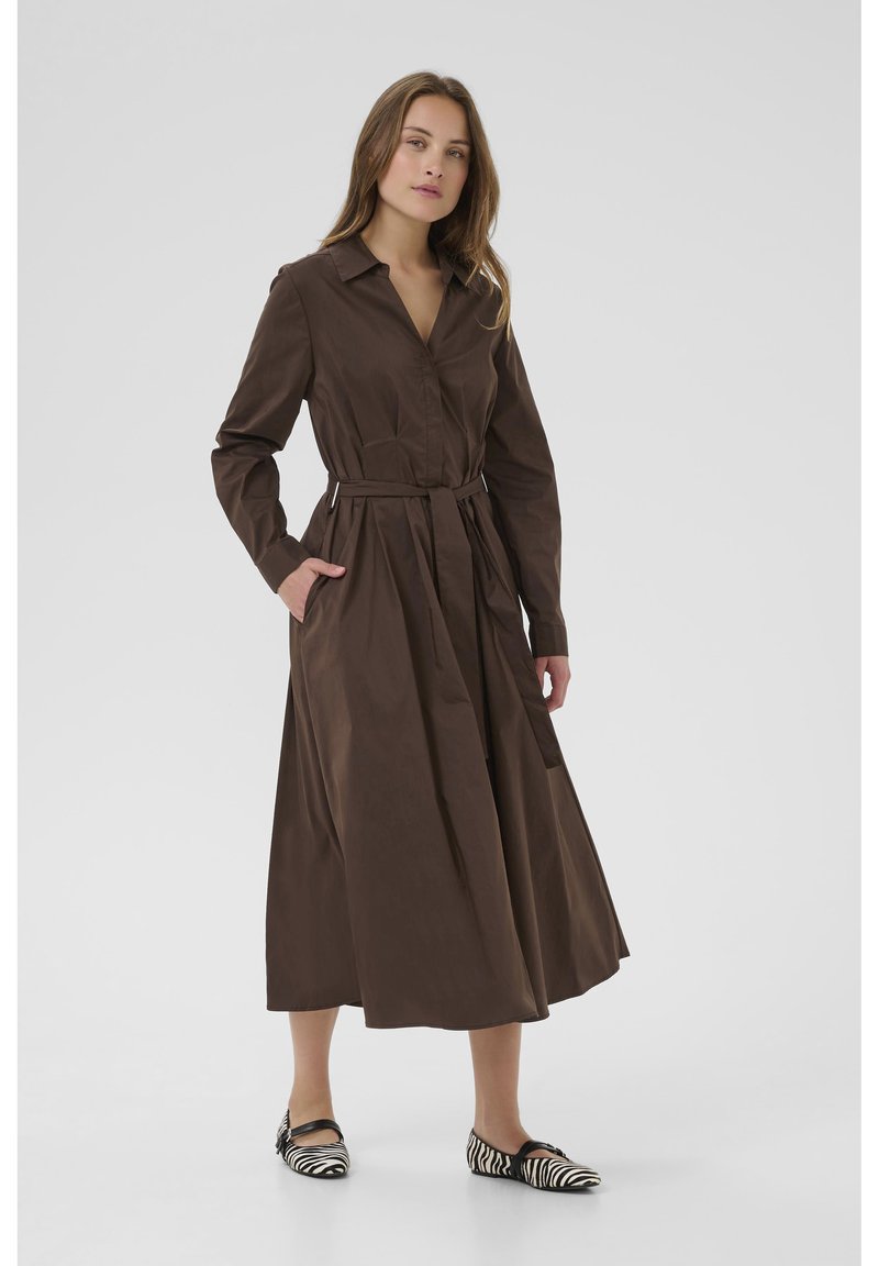 Brown long-sleeve shirt dress with a collar, belted waist, and side pockets. Styled with black and white striped ballet flats.
