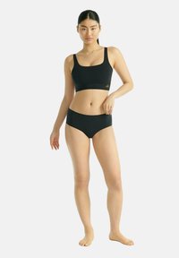 Schwarzer Sport-BH und passende Slips aus glattem Material. Der BH hat einen quadratischen Ausschnitt; die Shorts haben eine mittelhohe Silhouette.