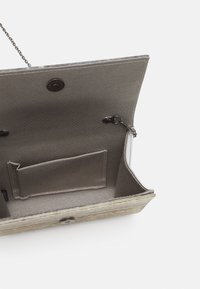 Borsa grigia testurizzata con tracolla a catena, dotata di una tasca interna e chiusura a scatto. Design elegante con una forma strutturata.