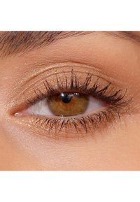 Primo piano di un occhio con iride marrone dorato, ciglia ben definite e ombretto bronzo metallico sulla palpebra, che mette in risalto la texture della pelle.