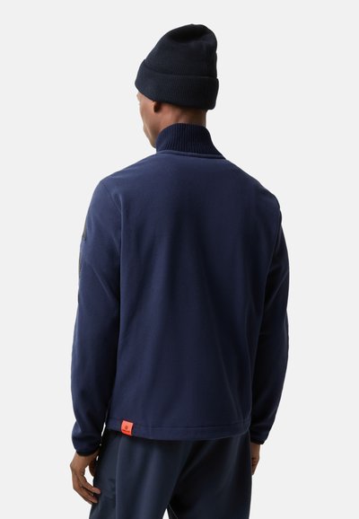 Marine fleece jacket met hoge kraag, lange mouwen en een contrasterend oranje label aan de onderkant. Glad textuur, minimalistisch ontwerp.