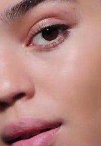 Close-up of a human face featuring smooth skin, brown eye with defined lashes, and slightly parted lips with a natural pink hue.