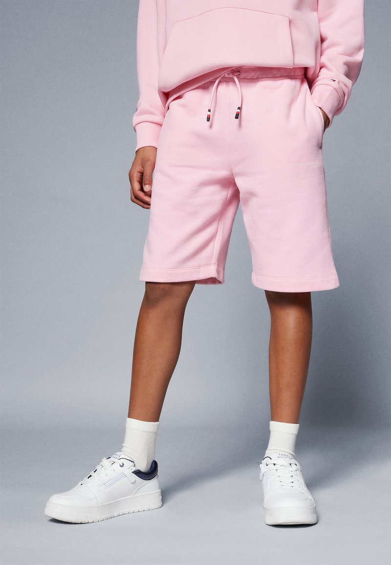 Rosa bomullsshorts med elastisk midja, sidofickor och uppvikta nederkanter. Kombinerat med vita sneakers och krämfärgade strumpor.