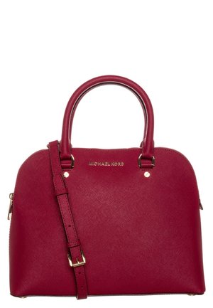 Czerwona torebka Michael Kors z zaokrąglonymi uchwytami, regulowanym paskiem na ramię i złotymi okuciami na białym tle.