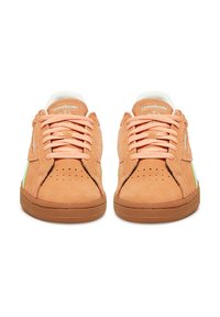 Egy pár barack színű Reebok Classic velúr sportcipő fűzős kivitelben, perforált orr résszel és gumi talppal, elölről nézve.