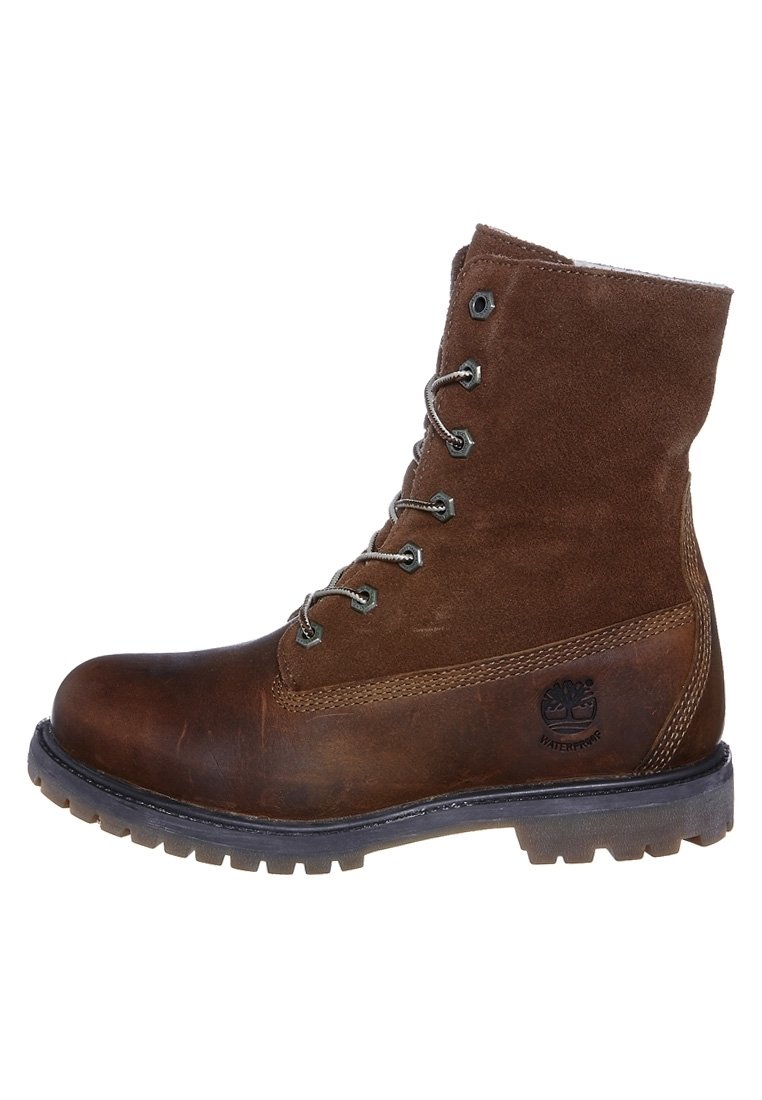 Botín de cuero marrón y ante con cordones, suela de goma y un logo en el lateral. Presenta un diseño robusto adecuado para uso al aire libre.