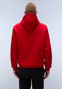 Felpa rossa con cappuccio regolabile, maniche lunghe e polsini a costine. Texture morbida e colore uniforme, senza motivi o loghi visibili.