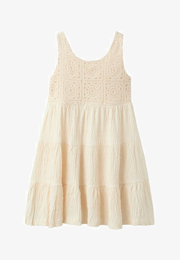 Kremowa sukienka bez rękawów z koronkowym kwiatowym górą i warstwową, fakturowaną spódnicą, zaprojektowana do noszenia na co dzień lub latem.