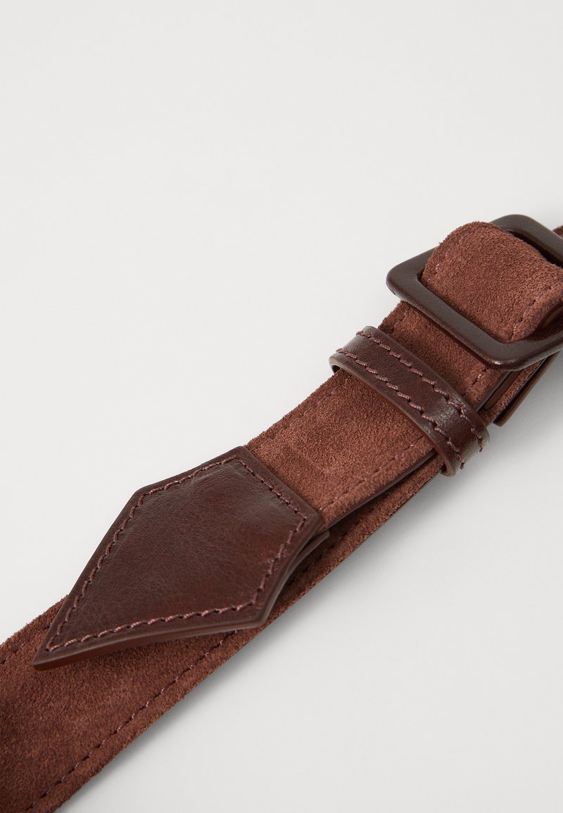 Brown leather strap featuring smooth and textured surfaces, with a diamond-shaped accent and a rectangular buckle. Durable stitching visible.