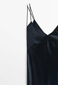 Robe noire à fines bretelles spaghetti, fabriquée en matériau brillant. Présente un décolleté en V et un panneau supérieur texturé se fondant dans une section inférieure lisse.