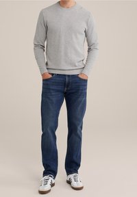 Gray knit sweater with a crew neckline, paired with blue denim jeans. Casual white sneakers with brown accents complete the look.