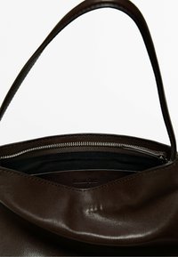 Dark brown leather handbag with a single strap, zipper closure, and visible black fabric interior lining.