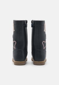 Bottes bottines en cuir bleu marine avec broderie de cœur rose et accents pailletés. Dotées d'une fermeture éclair latérale et de semelles en caoutchouc texturées.