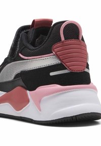 Sneaker nera con tomaia in rete e pelle, dettagli rosa, striscia argentata metallica, tacco arrotondato e suola intermedia bianca texturizzata.
