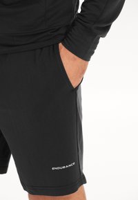 Svarta sportshorts i slät tyg, med en sidoficka och "ENDURANCE"-logotyp i vitt på vänster ben.